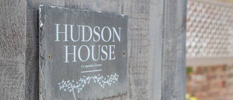 A sign on a wooden wall that reads 'HUDSON HOUSE Co-operative Terrace.'