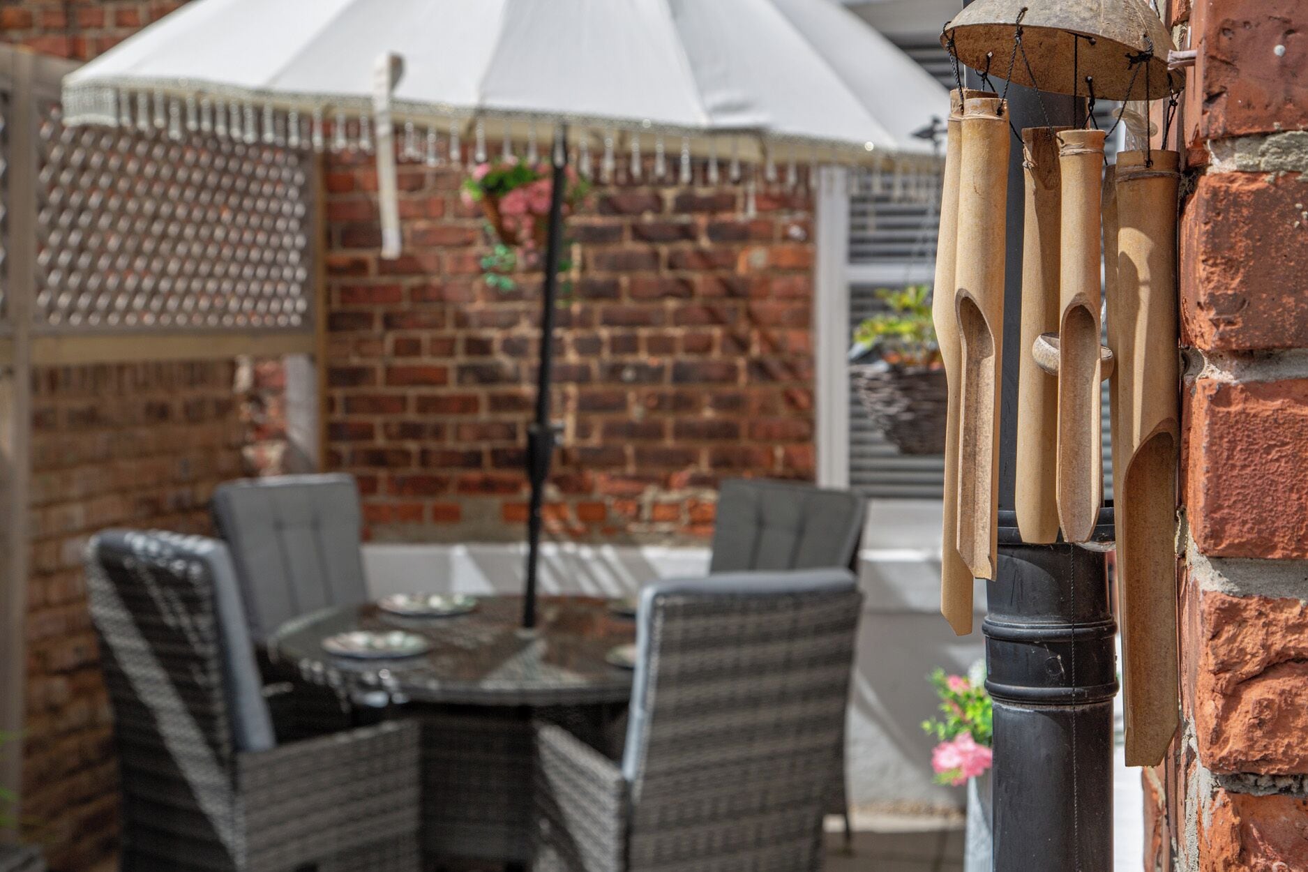 A patio with wicker furniture, a table, and a hanging umbrella.