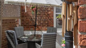 A patio with wicker furniture, a table, and a hanging umbrella.