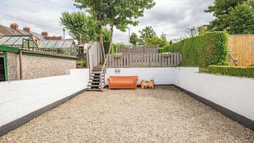 A backyard with a gravel path, a wooden bench, a small staircase, and a wooden fence.