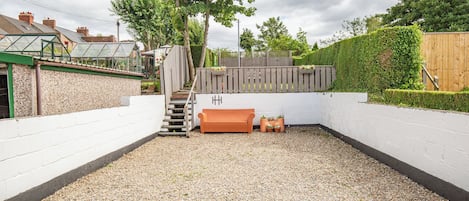 A backyard with a gravel path, a wooden bench, a small staircase, and a wooden fence.