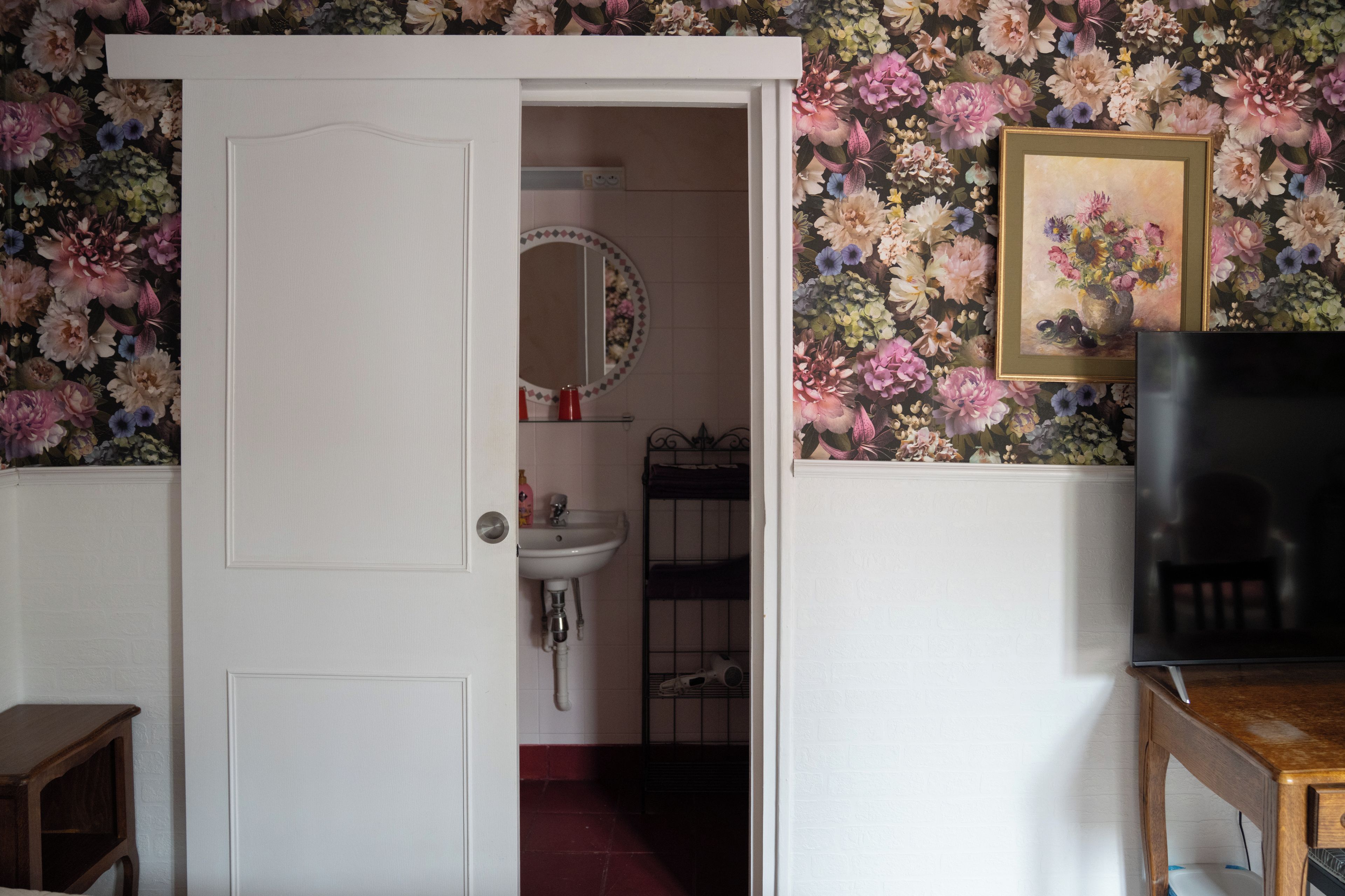 Una habitación con una puerta blanca que da a un baño con lavamanos y espejo.