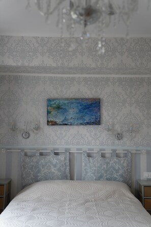 Un dormitorio con una cama, un cuadro en la pared y una araña.
