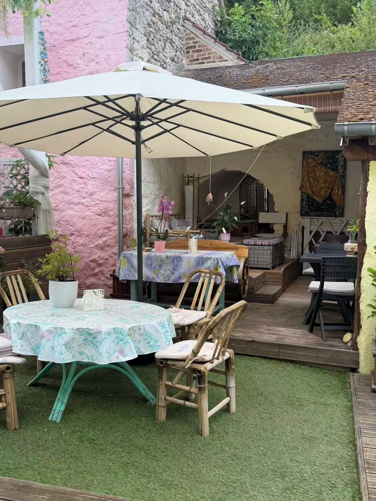 An outdoor patio with a table and chairs, a hanging chair, and a covered area with a table and chairs.