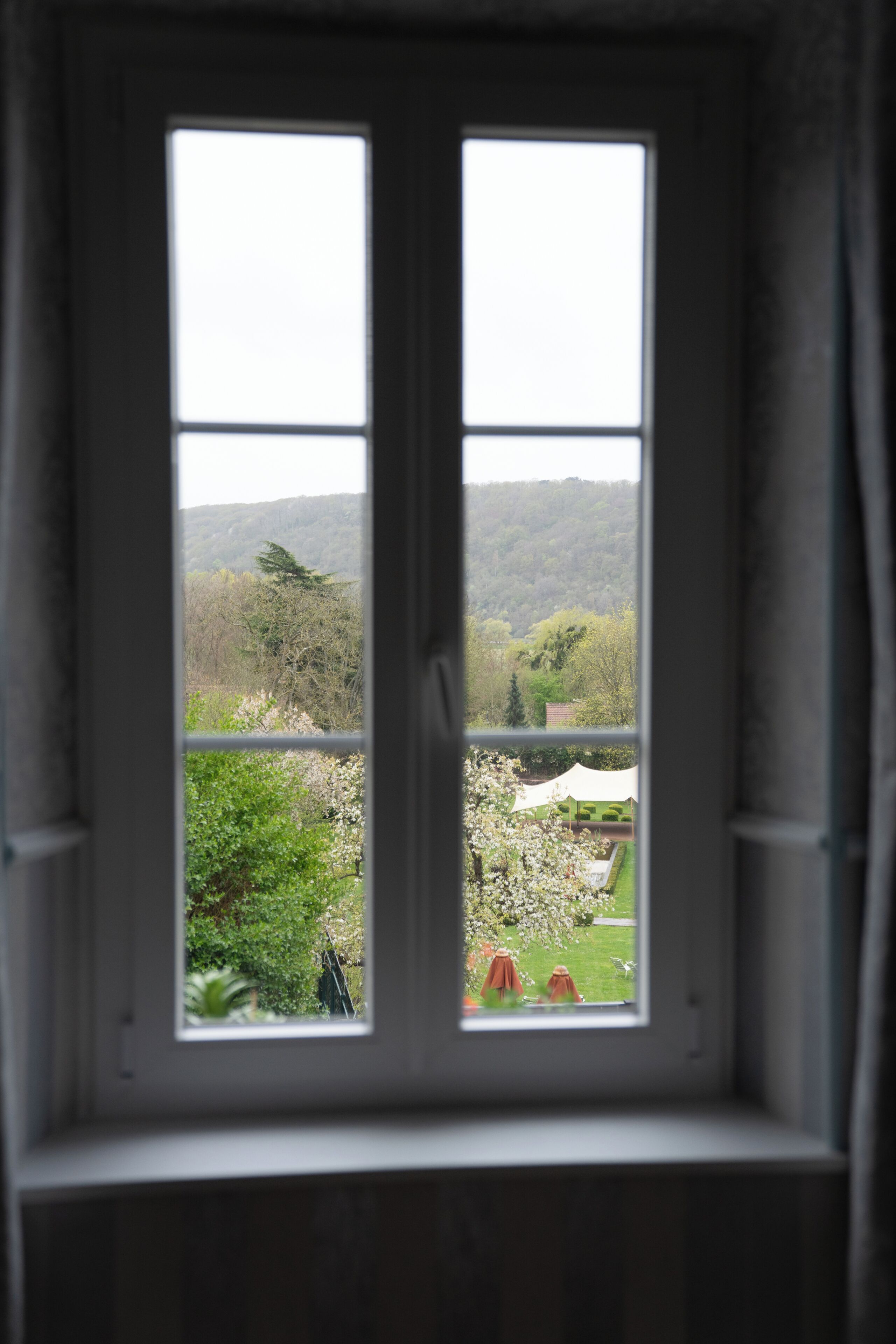 Ein Fenster mit Blick auf einen Garten und ein weißes Zelt.