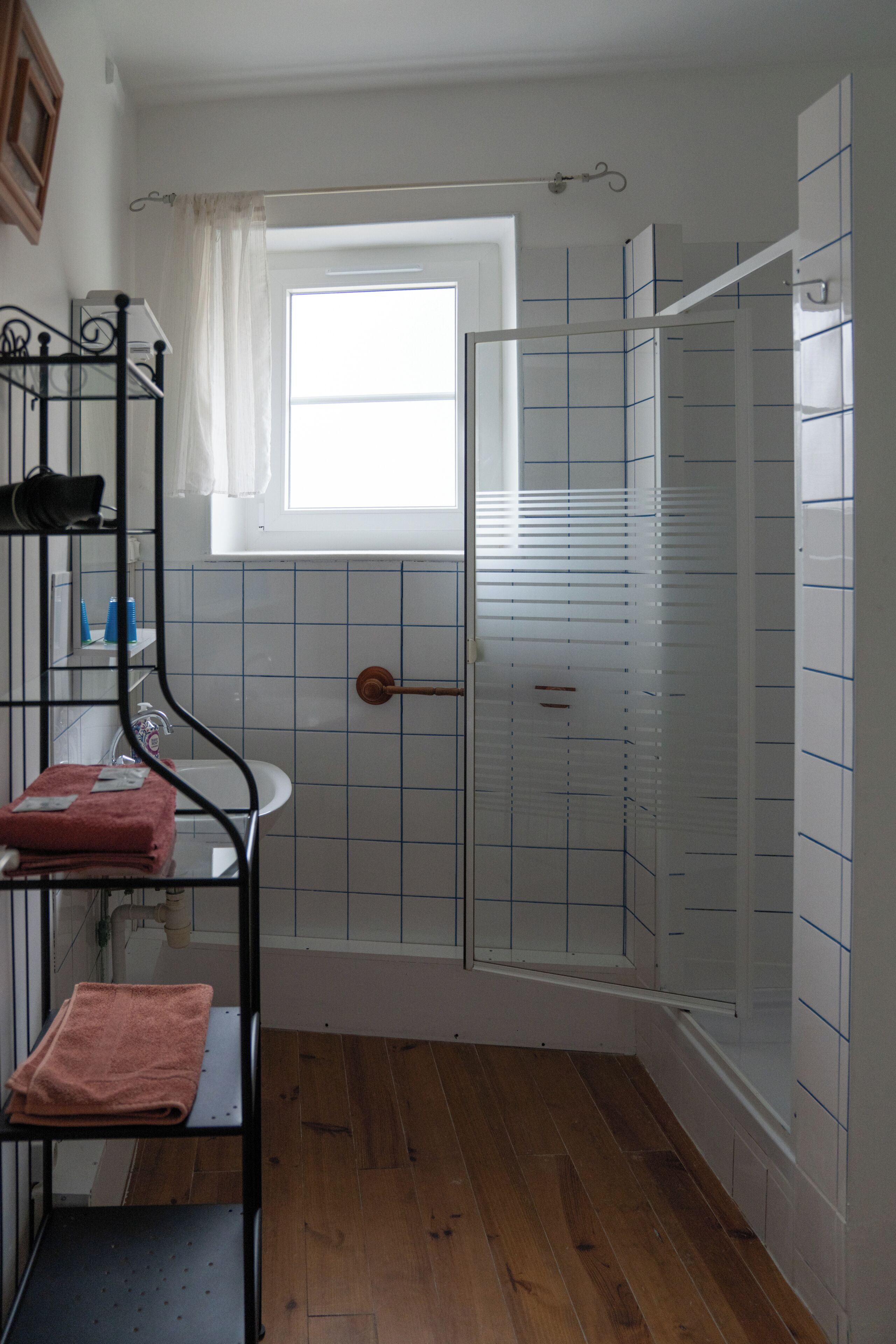 Een badkamer met een douche, een raam en een handdoekhouder.