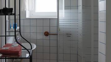 Een badkamer met een douche, een raam en een handdoekhouder.