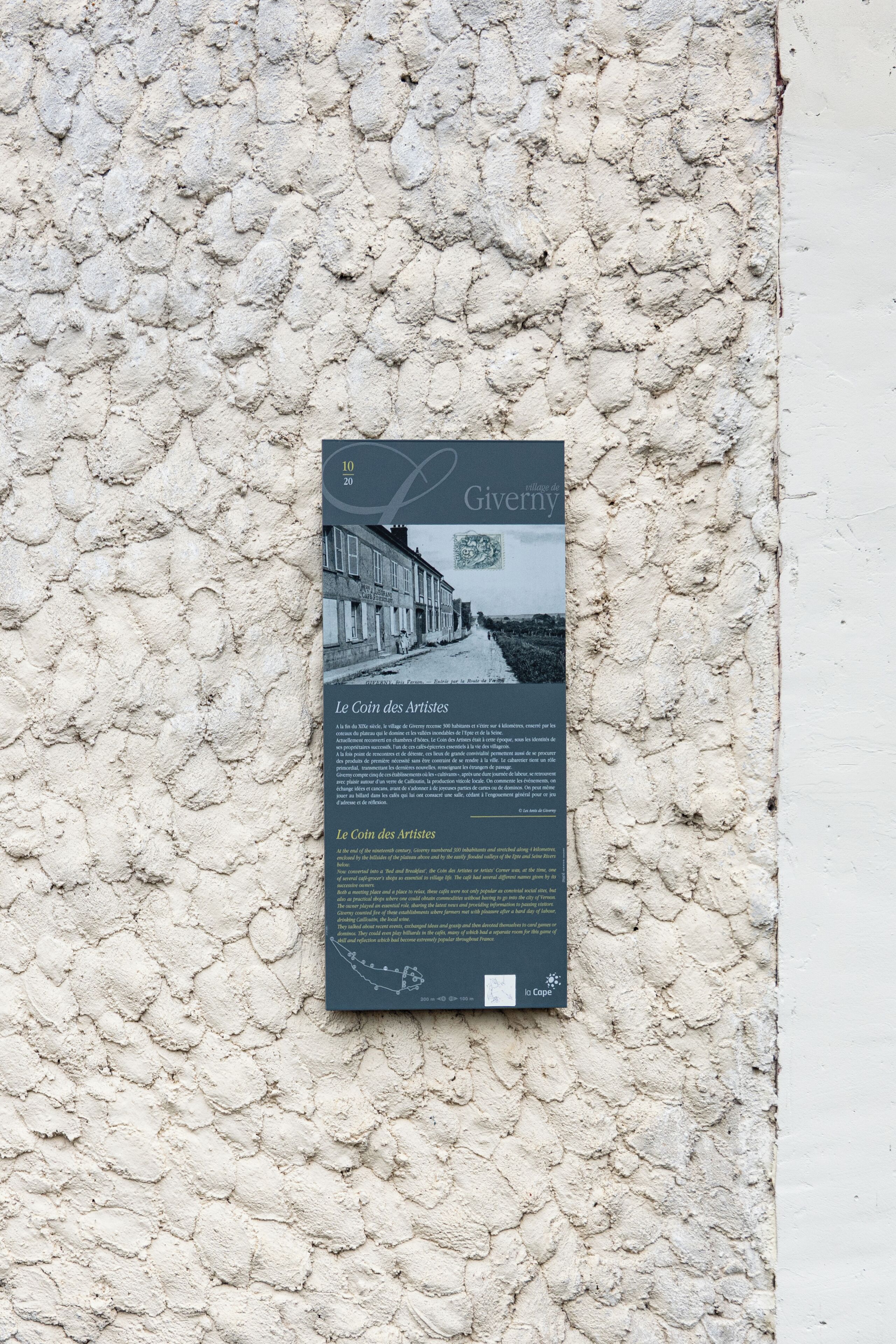 Una placa en una pared con textura, texto y una fotografía antigua.