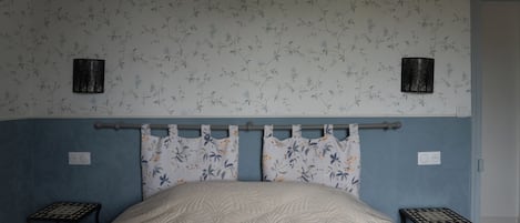 A bedroom with a bed, two nightstands, a headboard, and a wall with floral wallpaper.