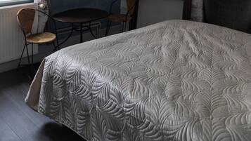 Une chambre à coucher comprenant un lit, une chaise, une table, un luminaire suspendu et une cheminée.