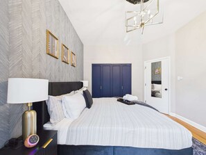 A bedroom with a bed, bedside table, lamp, and wardrobe.