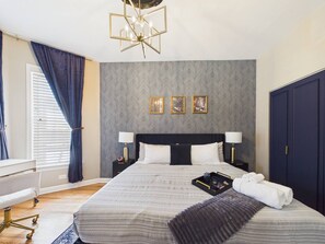 Ein Hotelzimmer mit einem großen Bett, zwei Nachttischen, einem Schreibtisch und einem Kleiderschrank.