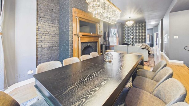 Un comedor moderno con una mesa larga, sillas, una chimenea y un candelabro.