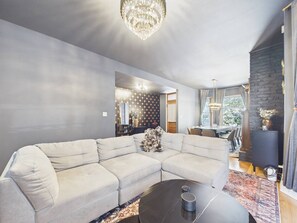 A modern living room with a sectional sofa, a round coffee table, and a chandelier.