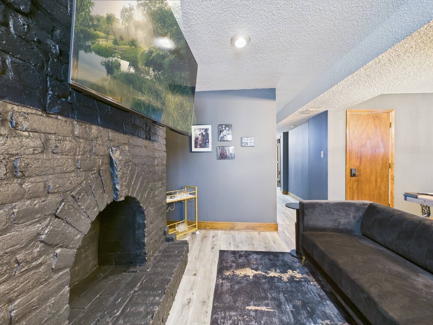 Um quarto com lareira de pedra, um sofá, uma porta de madeira e uma prateleira fixada na parede.