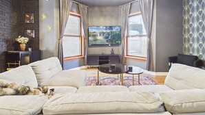 Una sala de estar con sofá, mesa de centro, televisor y candelabro.