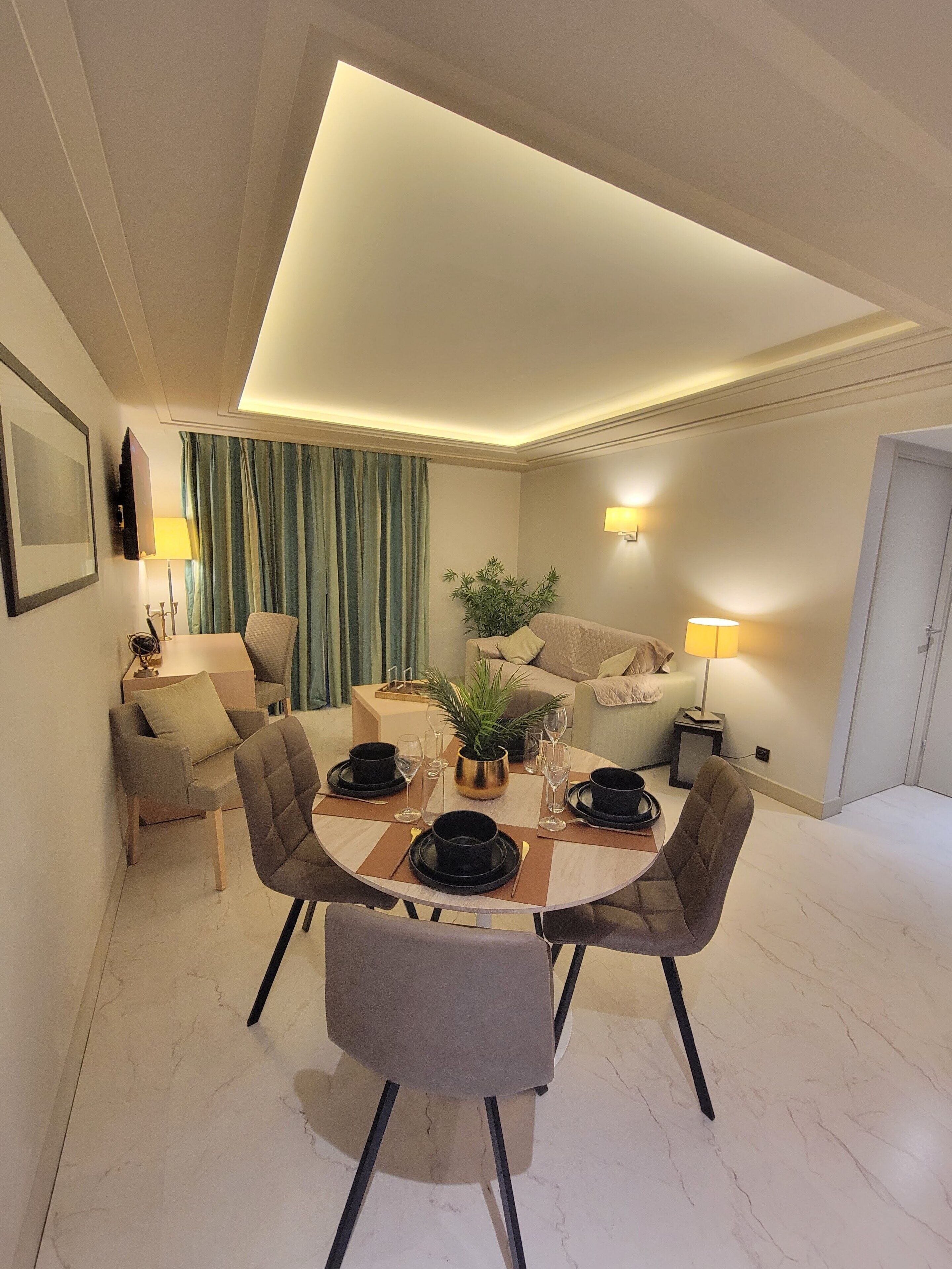 A modern dining area with a round table, chairs, and a plant centerpiece.
