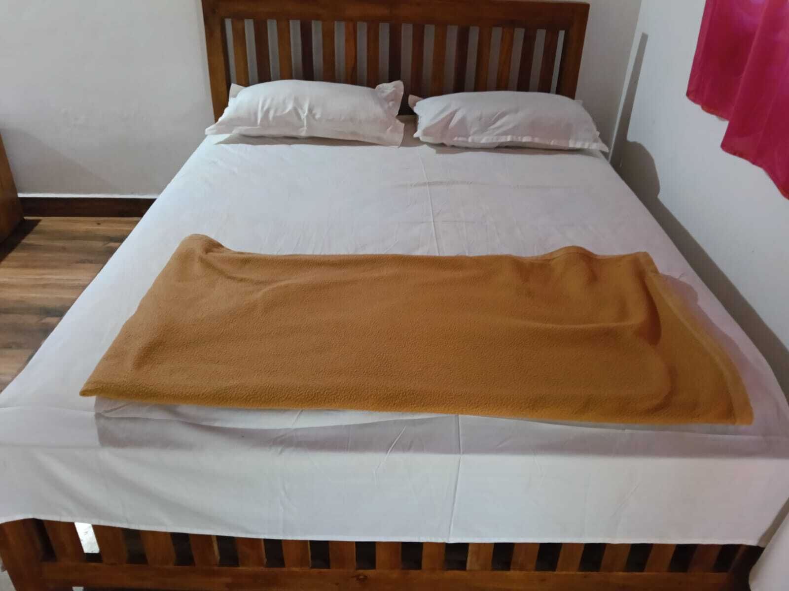 A bed with a white sheet, two white pillows, and a brown blanket.