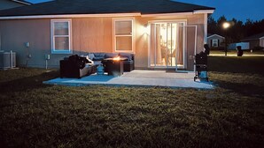 A residential house with a patio, outdoor seating, and a sliding glass door. - Jax Waterfront Retreat at Winchester Ridge (Jacksonville)