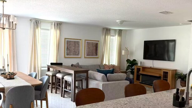 A modern living room with a dining area, kitchen, and a flat-screen TV mounted on the wall. - Jax Waterfront Retreat at Winchester Ridge (Jacksonville)
