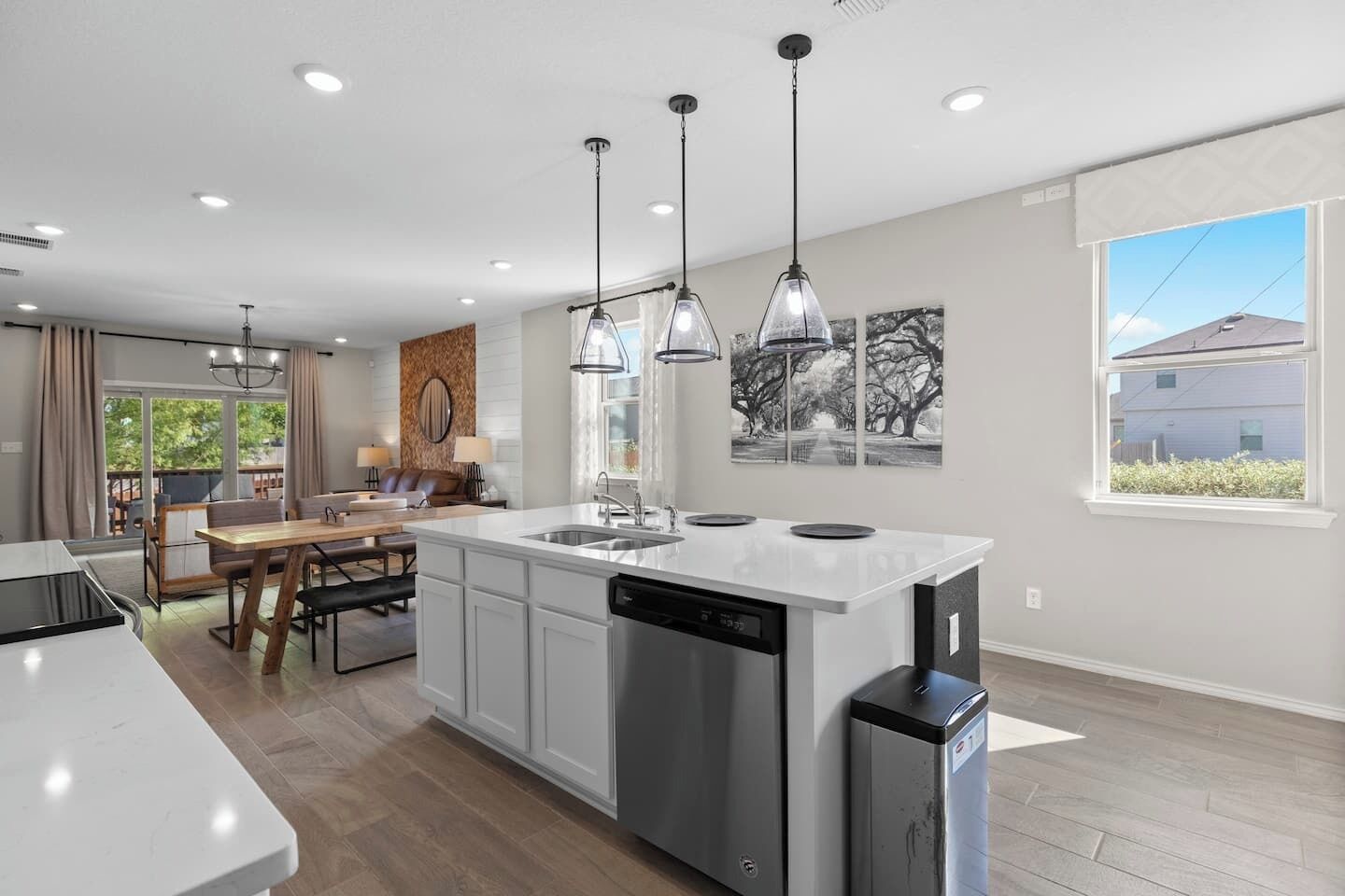A modern kitchen with a central island, pendant lighting, and a dining area with a view.