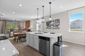 A modern kitchen with a central island, pendant lighting, and a dining area with a view. - USAF themed near Randolph Brooks AFB w/ Game Room (Converse)