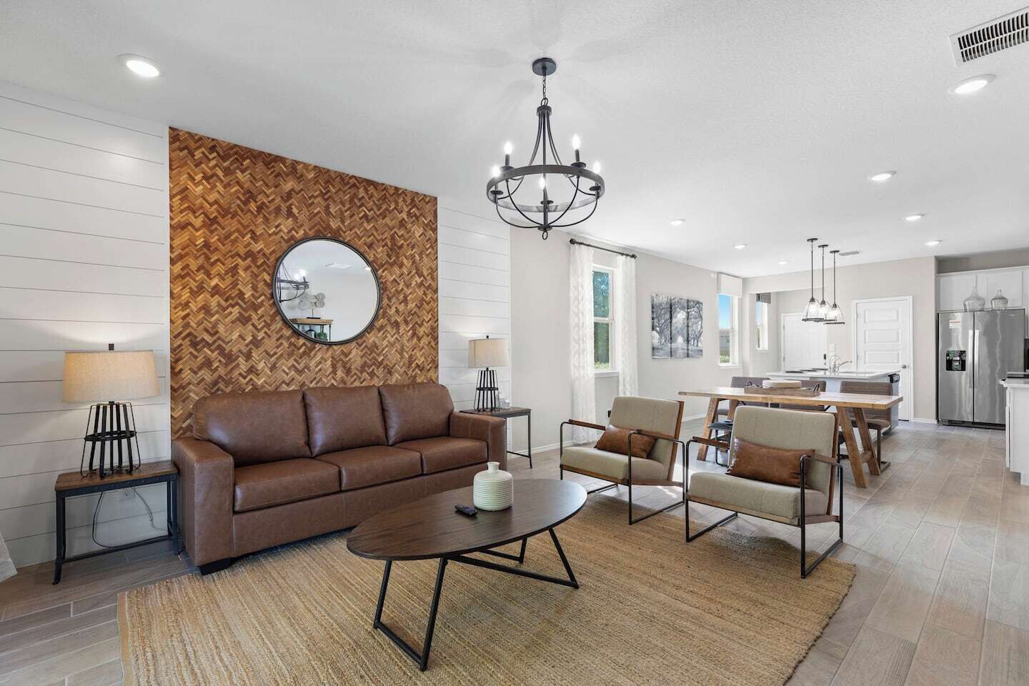 En moderne stue med sofa, stole, et sofabord og en lysekrone.