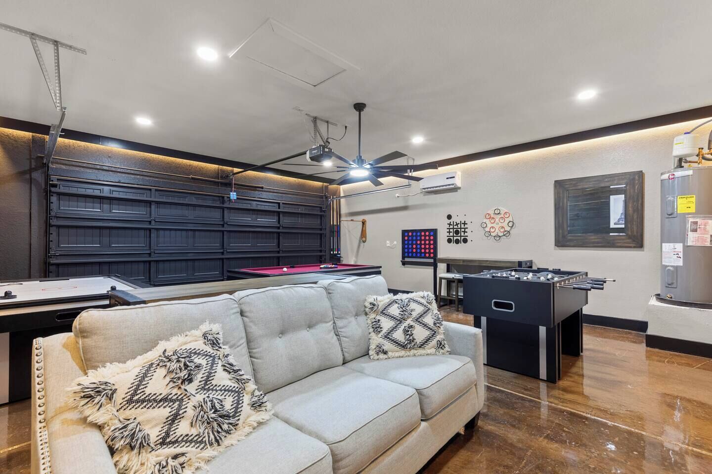 A modern living room with a pool table, sofa, and foosball table.