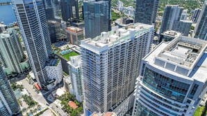 A high-rise urban area with multiple buildings, including a prominent white building with a green rooftop and a tall blue glass building. - Brickell Bay View Pool & Gym (Miami)