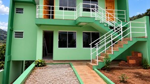 A modern two-story building with a green exterior, a central staircase, and a small front garden.