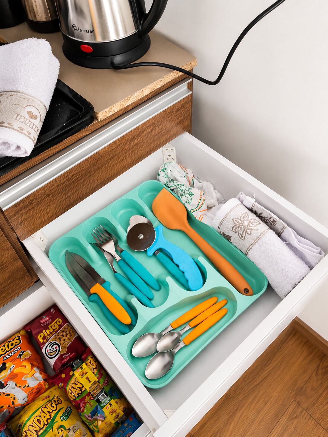 Un tiroir de cuisine contenant un compartiment pour ranger les aliments, avec des ustensiles et des collations à l’intérieur.