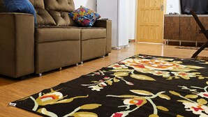 A living room with a sofa, a refrigerator, a wooden door, and a patterned rug.