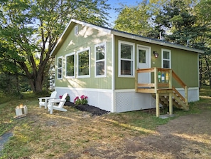 A small, single-story cabin with a porch, a fire pit, and a wooden deck. - Camp Avaliz - Ocean-view for 2 with a queen bedroom, kitchenette, Wi-Fi and AC (Gouldsboro)