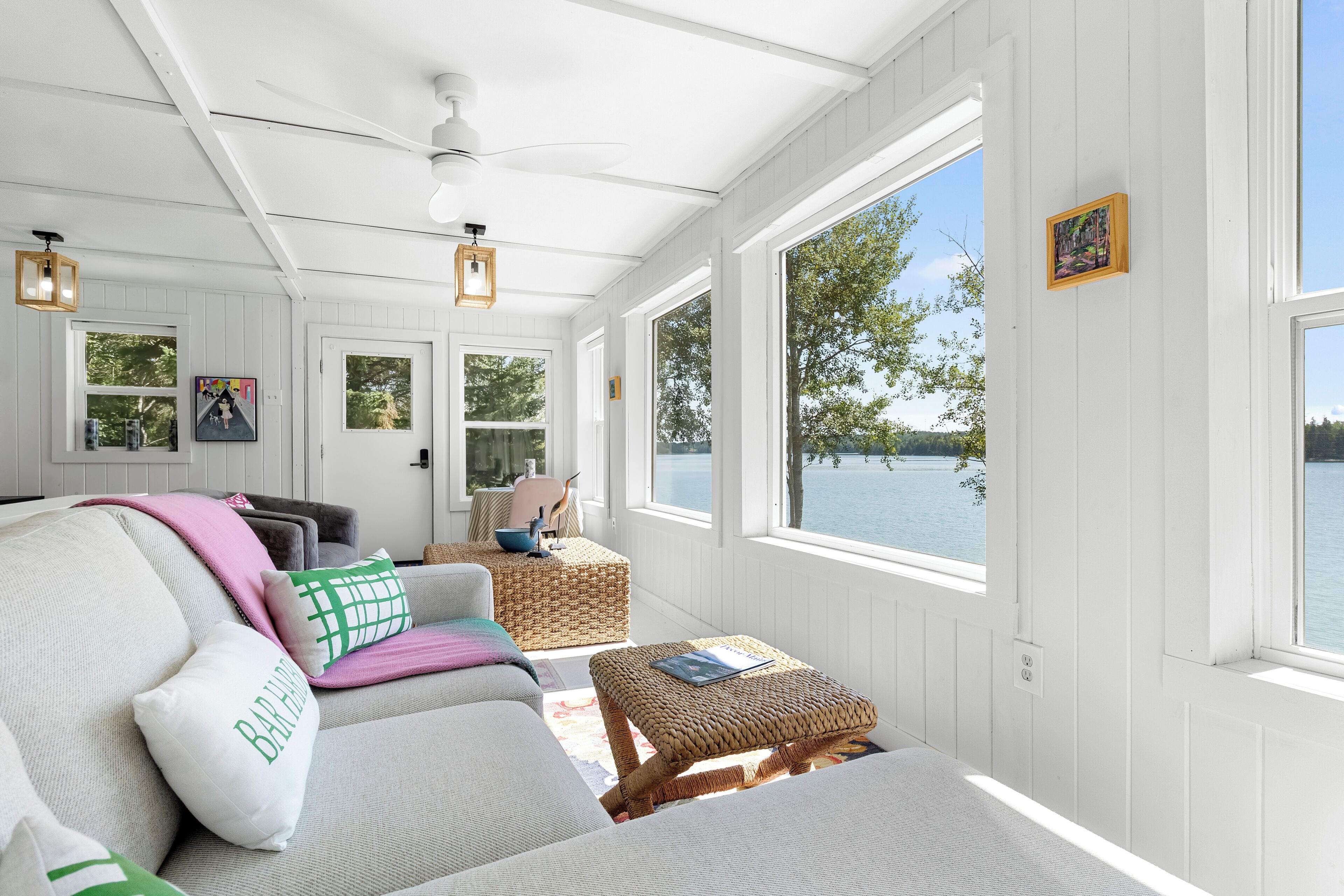 A cozy room with a sofa, a reading chair, and a window overlooking a body of water.