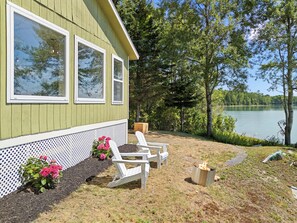 Una cabaña con terraza, dos sillas Adirondack y un brasero.