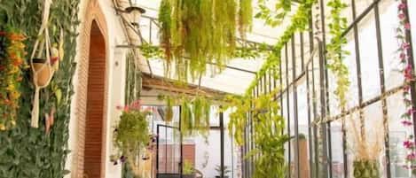 Un portico coperto con piante pensili, un tavolo e sedie.