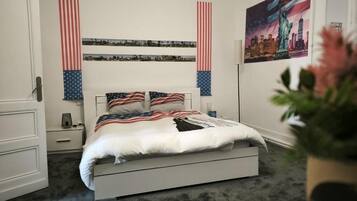 Une chambre à coucher avec un lit, une table de chevet, une étagère fixée au mur et un tableau encadré.