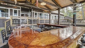Una barra de madera con superficie pulida, una escalera que sube a un nivel superior y vistas del entorno.