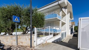 A multi-story building with a balcony, a pedestrian crossing sign, and a stone wall. - GuestHost - Cozy Balcony Apartment with Ocean View (Pineto)