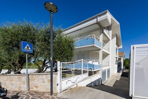 Ein mehrgeschossiges Gebäude mit einem Balkon, einem Fußgängerüberweg-Schild und einer Steinmauer.