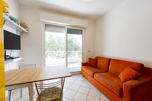 Ein Zimmer mit einer Couch, einem Tisch, Stühlen, einem Fernseher und einem Balkon mit Blick.