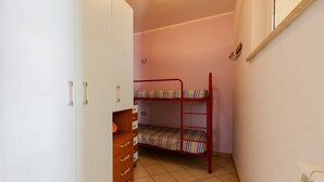 A narrow room with a bunk bed, a wardrobe with drawers, and a radiator. - GuestHost - Cozy Balcony Apartment with Ocean View (Pineto)