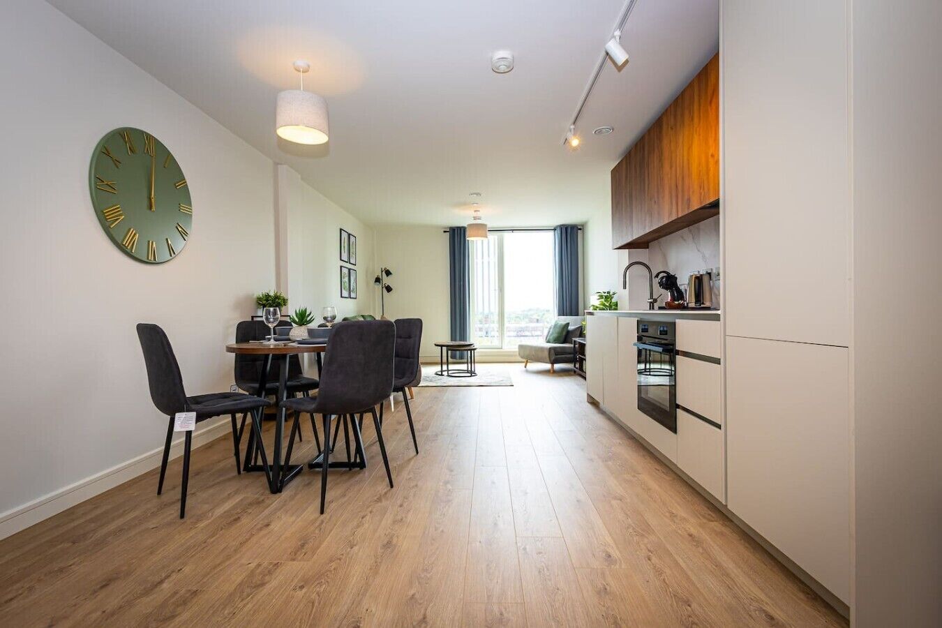 A modern apartment with a dining area, kitchen, and a large window.