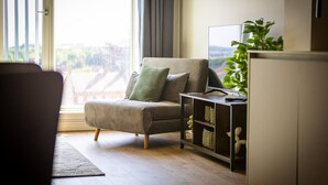 A modern living room with a sofa, a side table, and a plant. - Birmingham City Retreat No 151 (Birmingham)