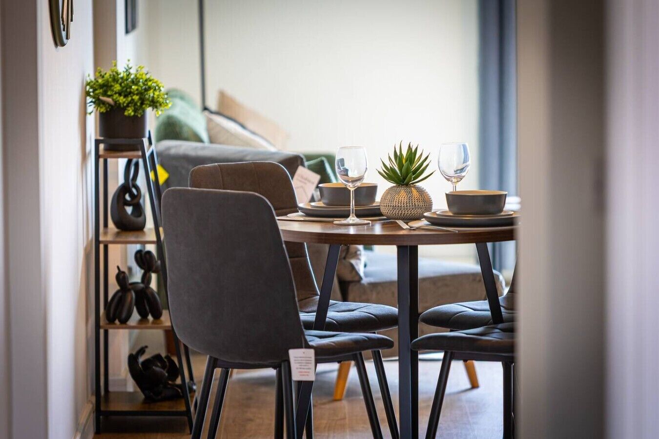 A dining area with a table set for two, featuring a plant, a pineapple, and a bowl.