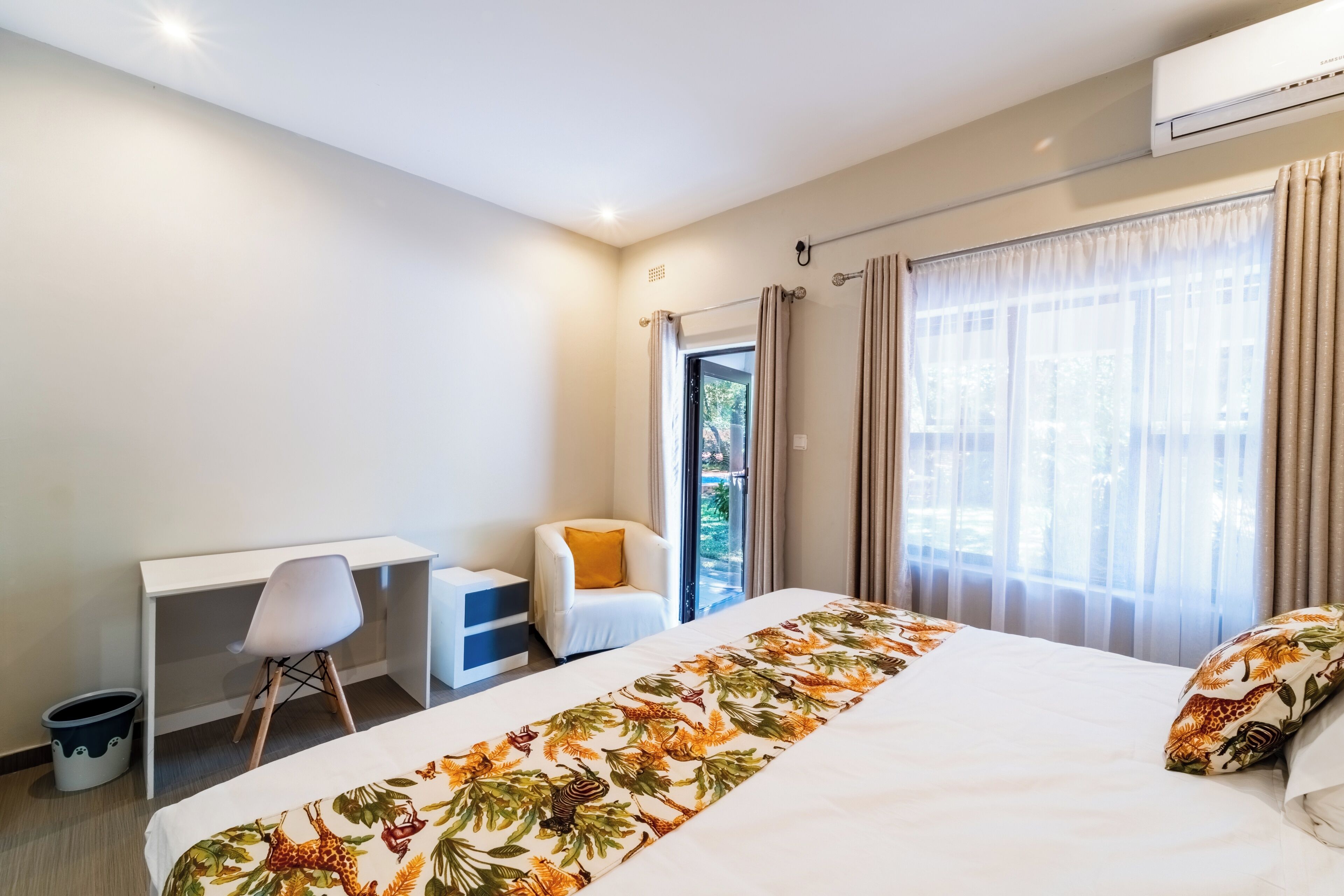 Une chambre d’hôtel avec un lit, un bureau, une chaise et une vue sur l’extérieur.