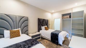 A hotel room with two beds, a wardrobe, and a desk.
