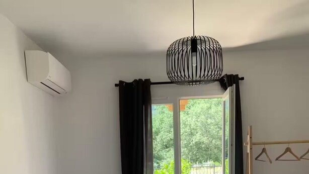 A bedroom with a bed, white pillows, a hanging light fixture, a window with curtains, and a view of the outdoors. - Les Albères Bed & Breakfast Suite with a view of the pool and terrace (Villelongue-dels-Monts)