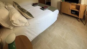 Una camera d'albergo con un letto, una televisione, un armadio e tre quadri appesi al muro.
