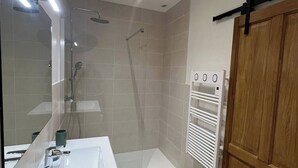 Un bagno moderno con doccia, lavandino e specchio.
